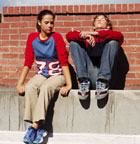 Teens sitting by brick wall
