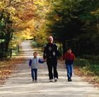 Father and kids walking in the fall down a road