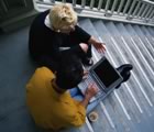 Two friends with laptop on stairs