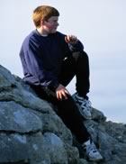 Boy sitting on rocks beside water