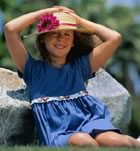 Girl sitting on the rocks with sun hat
